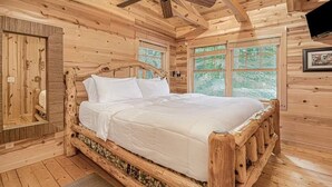 A wooden cabin bedroom with a bed, wooden walls, and large windows. - Cozy Cabin Getaway with Private Hot Tub & Lake Access in Saugatuck! (Saugatuck)