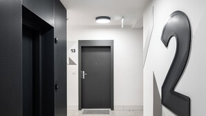 Un pasillo moderno con una puerta oscura, un cartel grande con el número 2 y una lámpara en el techo.
