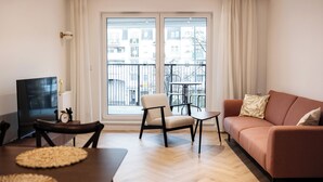 Una sala de estar con sofá, sillón, mesa de centro, televisor y una mesa de comedor con individuales.