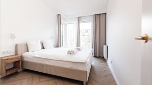 Un hotel moderno con una cama grande, una mesita de noche y vistas a la ciudad desde la ventana.