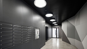 Un pasillo moderno con casilleros, iluminación empotrada y diseño geométrico en la pared.