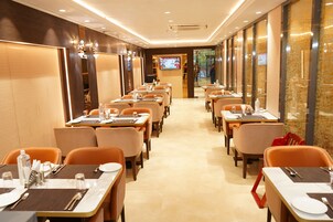 A restaurant with multiple tables and chairs, a television screen, and a well-lit interior.
