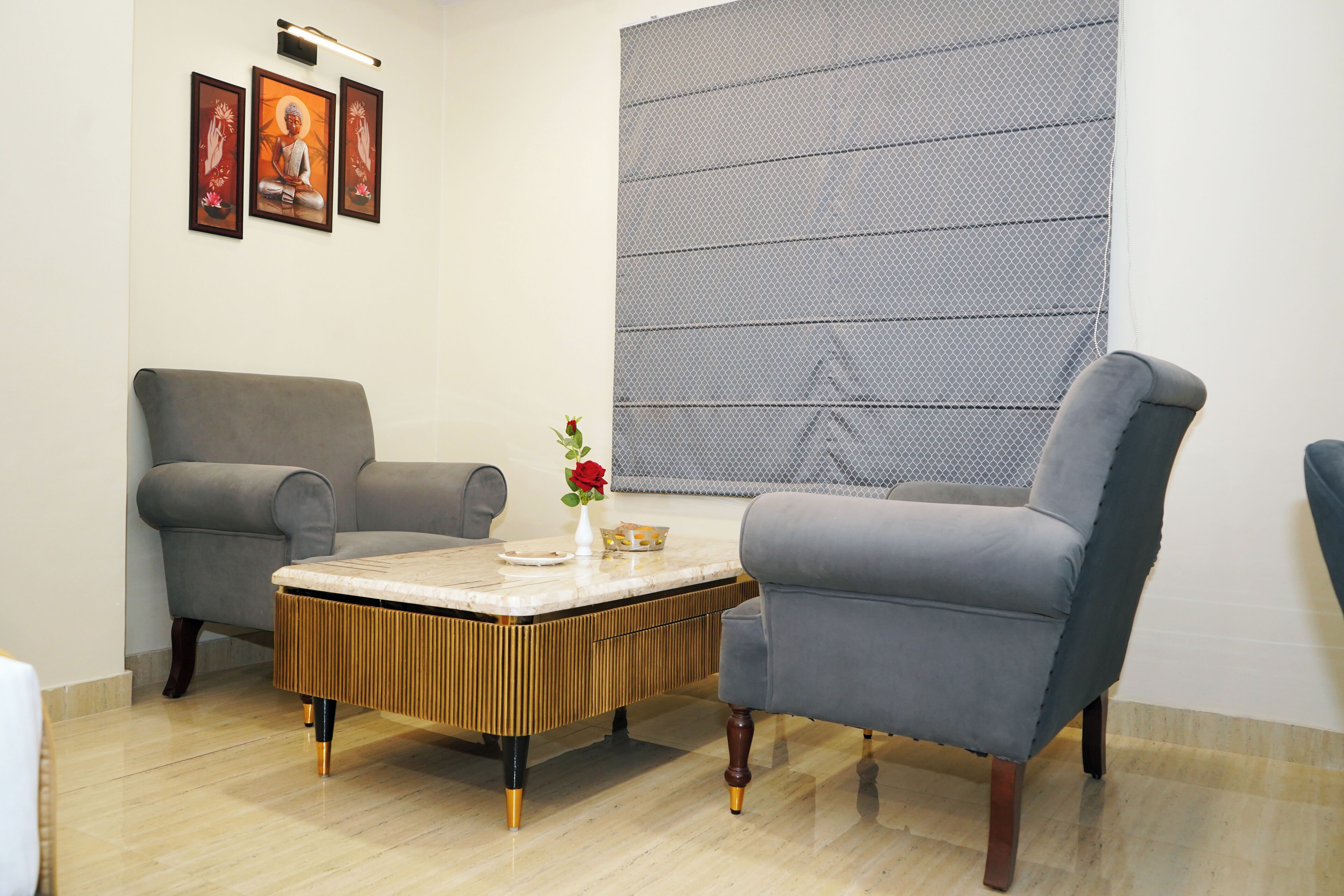 Una habitación con dos sillones grises, una mesa de centro de madera y un ventanal con mosquitero.