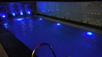 Una piscina con iluminación azul y una pared de vidrio.