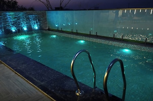 Ein Schwimmbecken mit Wasserfall und beleuchteten Stufen.