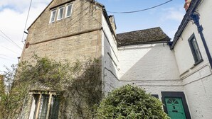 A narrow alleyway with a brick building on the left and a white building on the right. There is a green door on the white building. - Host Stay Apartment 6 Church Walk (Melksham)