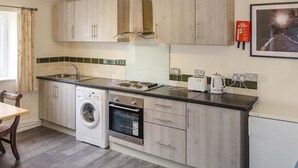 A compact kitchen with a washing machine, oven, and toaster. - Host Stay Apartment 4 Church Walk (Melksham)