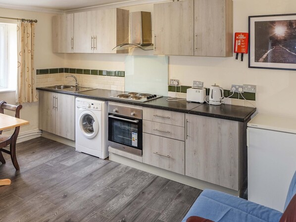 A compact kitchen with a washing machine, oven, and toaster. - Host Stay Apartment 4 Church Walk (Melksham)