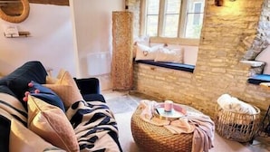 A cozy room with a stone wall, a cushioned bench, and a woven basket. - Host Stay Gwenelin Cottage (Evesham)