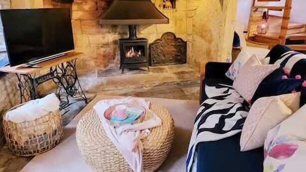 A cozy living room with a stone fireplace, a television, and comfortable seating. - Host Stay Gwenelin Cottage (Evesham)
