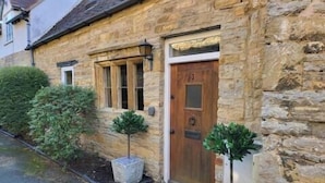 A stone house with a wooden door, a small window, and a potted plant. - Host Stay Gwenelin Cottage (Evesham)