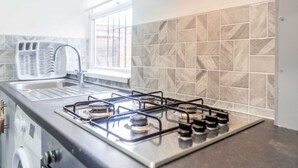 A kitchen with a gas stove, a washing machine, and a window with a view. - Host Stay Bambro Apartment (Sunderland)