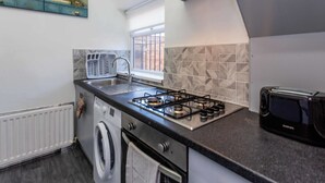 A compact kitchen with a gas stove, a built-in oven, a washing machine, and a toaster. - Host Stay Bambro Apartment (Sunderland)