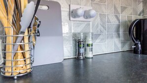 A kitchen counter with a cutting board, salt and pepper shakers, and a kettle. - Host Stay Bambro Apartment (Sunderland)