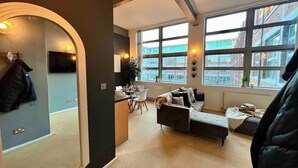 A modern living room with a sofa, a dining table, and a large window offering a city view. - Host Stay Great Hampton Apartment (Birmingham)