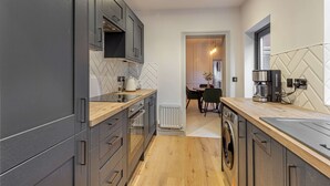 A modern kitchen with grey cabinets, a wooden countertop, and a herringbone-patterned backsplash. - Host Stay Barton Road Retreat (Hereford)