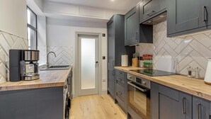 A modern kitchen with grey cabinets, a wooden countertop, and a built-in oven. - Host Stay Barton Road Retreat (Hereford)