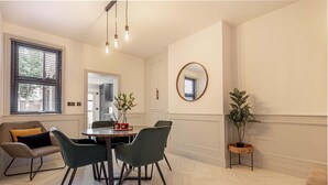 A dining area with a round table, four chairs, a vase with flowers, and a hanging light fixture. - Host Stay Barton Road Retreat (Hereford)