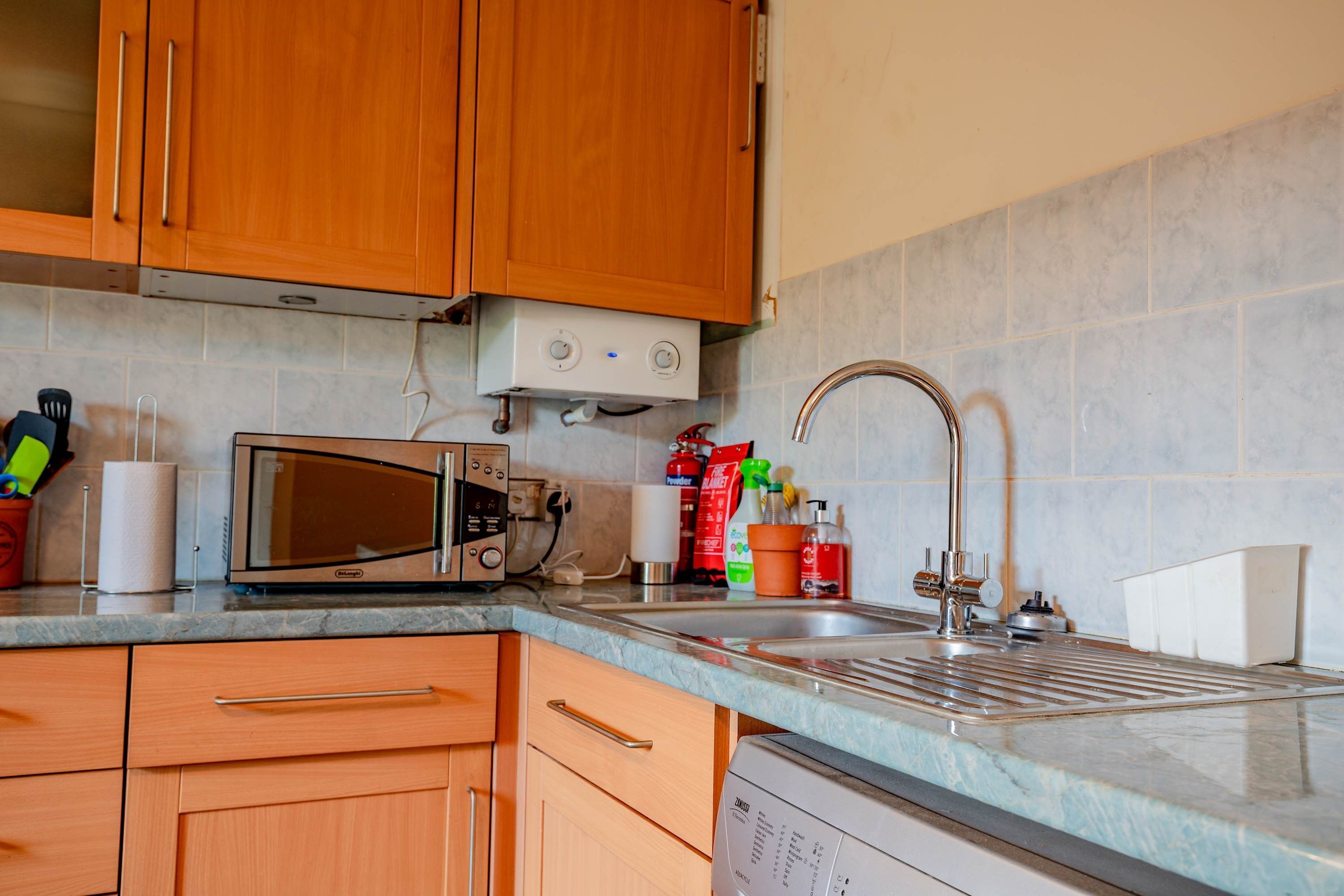 A kitchen with wooden cabinets, a stainless steel sink, a microwave, and a dishwasher.
