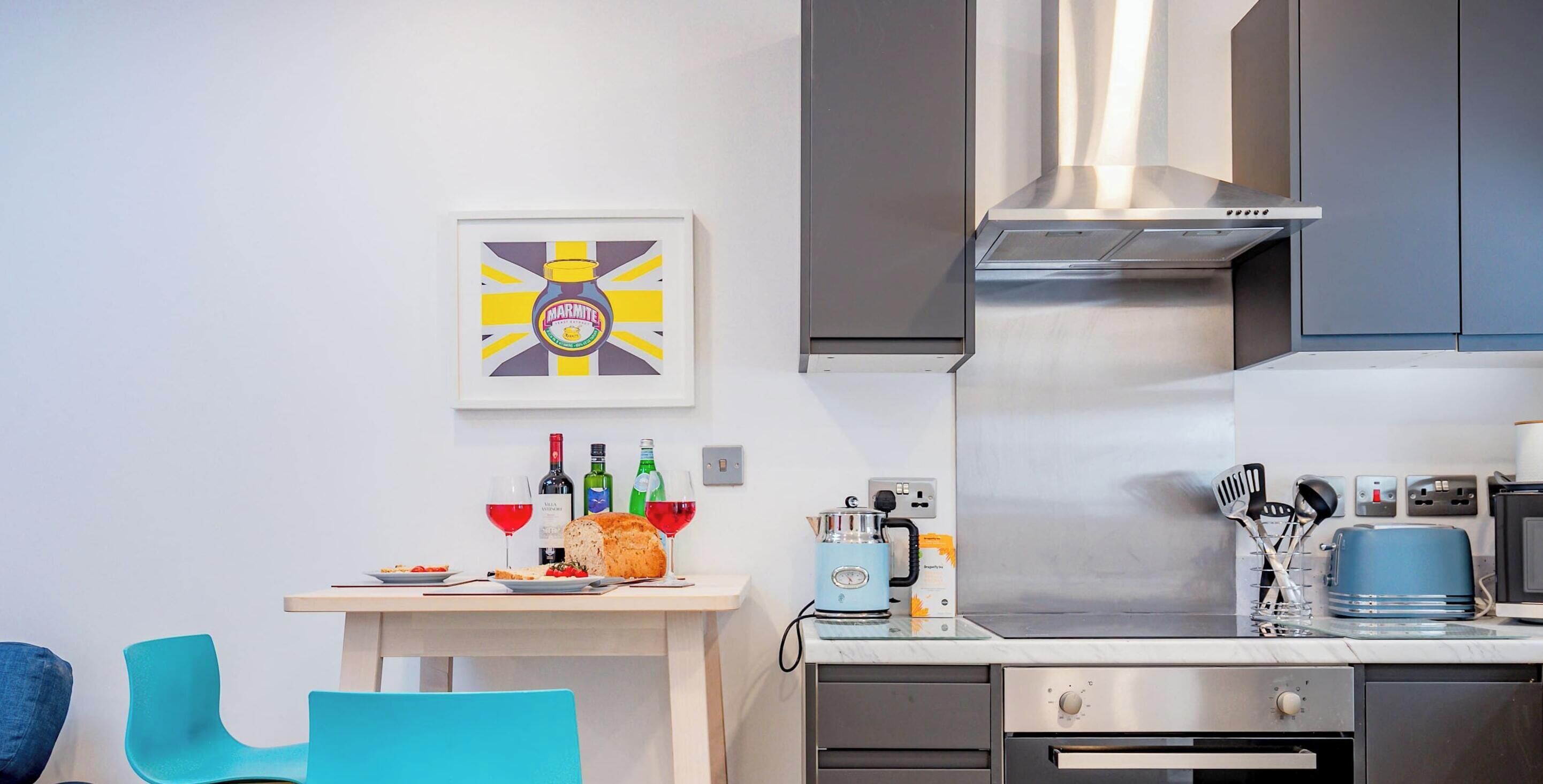 Eine moderne Küche mit Dunstabzugshaube aus Edelstahl, einer Arbeitsplatte mit Toaster und einem Essbereich mit Tisch und Stühlen.