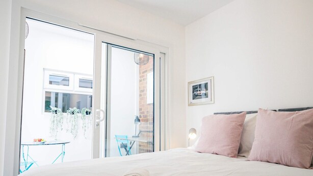 A bedroom with a bed, a nightstand, a lamp, and a window. - Host Stay Croydon Road Abode (Caterham)