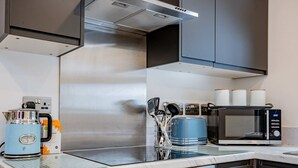 A modern kitchen with a kettle, toaster, and microwave. - Host Stay Croydon Road Abode (Caterham)
