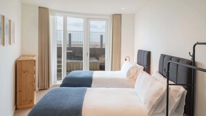 Ein Hotelzimmer mit zwei Betten, einem Holzschrank und einem Balkon mit Blick auf den Strand.
