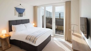 Ein modernes Hotelzimmer mit einem großen Bett, einem Fernseher und einem Balkon mit Blick.