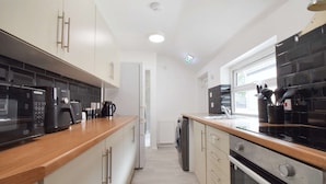 A modern kitchen with a microwave, coffee maker, and oven. There is a window providing natural light and a view of the outside. - Host Stay Church Drive (Mansfield)