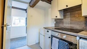 Una cucina con mobili bianchi, soffitto in legno e una finestra.