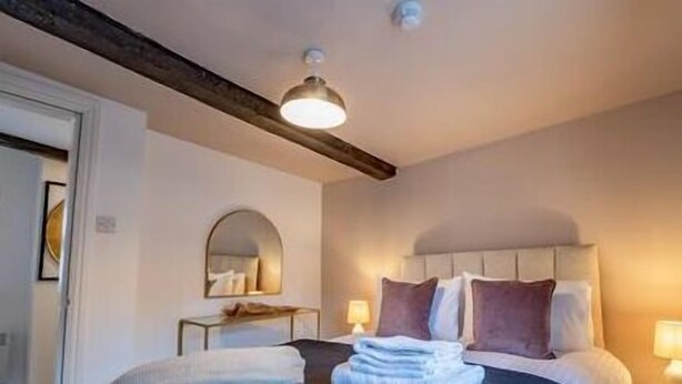 Una camera da letto con un letto, lampade sui comodini, uno specchio e una trave in legno al soffitto.