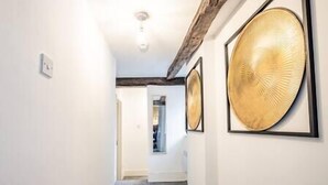 Un corridoio con pareti bianche, soffitto in legno e due ampi pannelli decorativi dorati sulla destra.