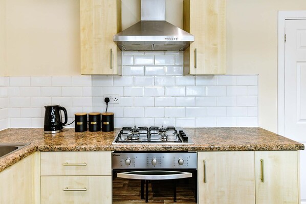 A kitchen with a gas stove, a built-in oven, and light wooden cabinets.