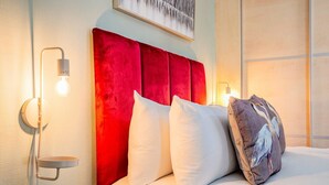 A hotel room with a red upholstered headboard, white bedding, and wall-mounted lighting. - Host Stay Somerset Road House (Birmingham)