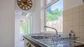 A kitchen with a window, a dish rack, and a clock on the wall. - Host Stay Somerset Road House (Birmingham)