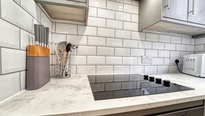 Une cuisine avec un dosseret de carrelage blanc, une plaque de cuisson à induction noire et un four à micro-ondes.