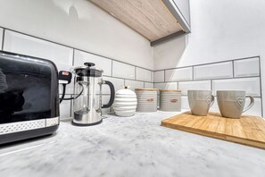 Eine Küche mit Kaffeemaschine, Mikrowelle und Aufbewahrungsbehältern auf der Arbeitsfläche.