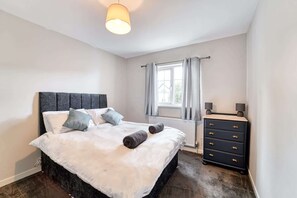 Une chambre à coucher avec un lit, une commode et une fenêtre avec des rideaux.