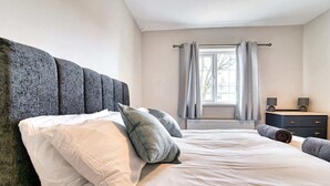 A bedroom with a large bed, a dresser, and a window with curtains. - Host Stay Birches Barn (Wolverhampton)