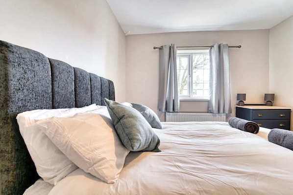 A bedroom with a large bed, a dresser, and a window with curtains. - Host Stay Birches Barn (Wolverhampton)