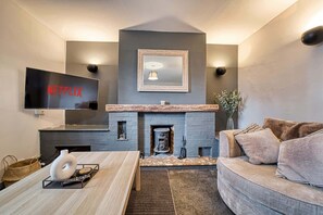 Un salon moderne avec une cheminée, un téléviseur à écran plat et un canapé confortable.