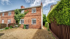 A two-story brick house with a garden area, a wooden fence, and a green bin. - Host Stay Birches Barn (Wolverhampton)