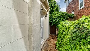 A narrow alleyway between two buildings, one with a white facade and the other with a brick exterior. - Host Stay Birches Barn (Wolverhampton)