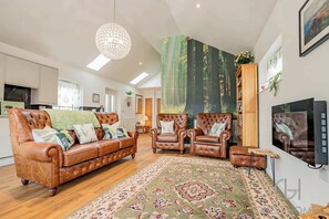 A spacious living room with a large sofa, two armchairs, a coffee table, and a TV. - Host Stay Little Highlands (Tenbury Wells)