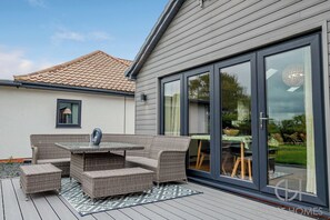 An outdoor patio with wicker furniture, a glass-top table, and a patterned rug. - Host Stay Little Highlands (Tenbury Wells)
