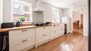Une cuisine moderne avec des meubles blancs, un plan de travail en bois et une cuisinière intégrée.