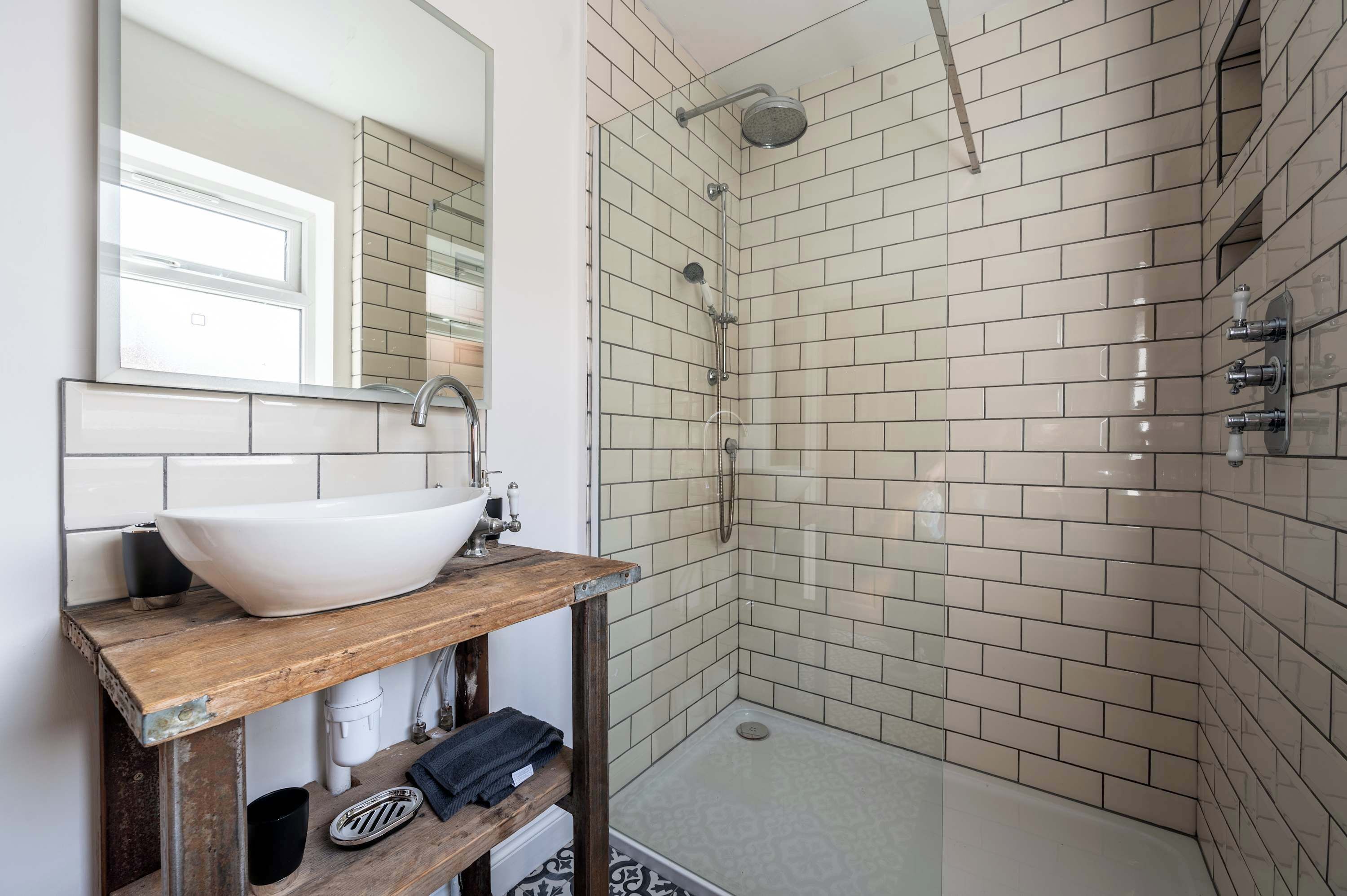 A modern bathroom with a white sink, wooden vanity, and a glass shower enclosure.