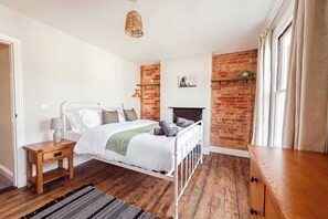 A bedroom with a white bed, wooden nightstand, and a brick accent wall. - Host Stay Sherrington Road Abode (Ipswich)