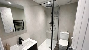 Une salle de bain moderne avec une douche à parois de verre, un lavabo blanc et des toilettes.
