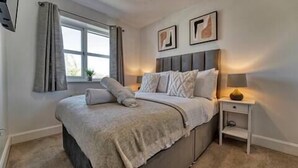 A bedroom with a bed, nightstand, lamp, window, curtains, and two framed pictures on the wall. - Host Stay Walkers Lane House (Worcester)